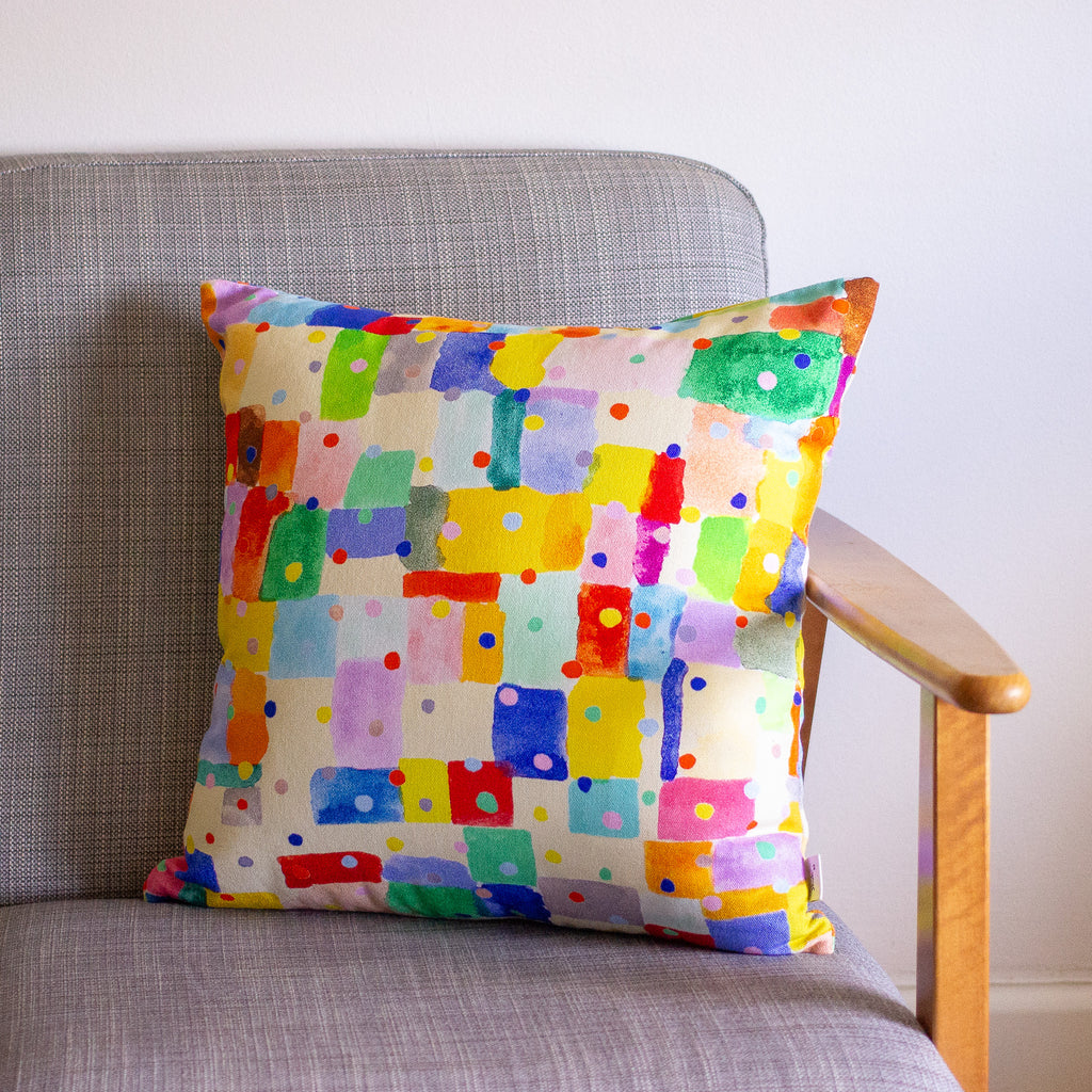 Colorful patterned cushion on a gray chair with a wooden armrest.