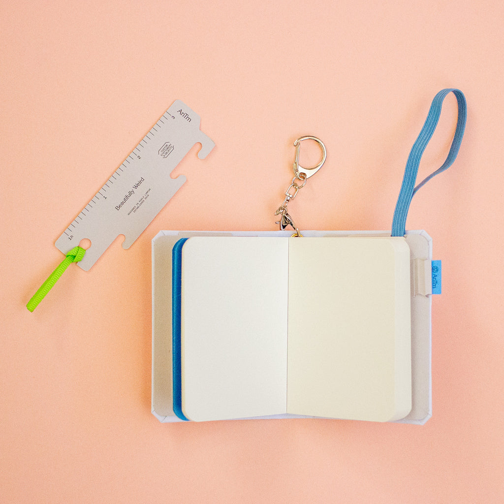 Open notebook with a keychain and ruler on a peach background