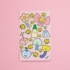 A rectangular pink sticker featuring cute hand-drawn smiley-face illustrations, including yellow flowers, a pink bow, and small abstract shapes, photographed on a solid pink background.