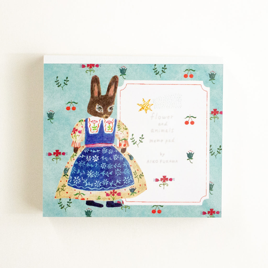 A notebook featuring an illustrated rabbit in a floral dress on a light blue background.