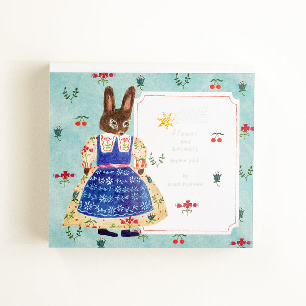 A notebook featuring an illustrated rabbit in a floral dress on a light blue background.
