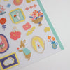 A close-up of a sticker sheet featuring cute bunny illustrations in various poses, decorated with colorful flowers, leaves, and frames on a white background.