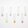 Set of six floral shaped ceramic charms on chains against a white background