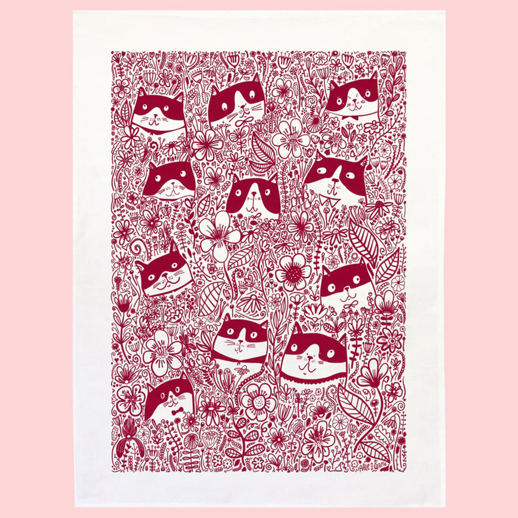 Patterned tea towel with red cat and floral design on a pink background