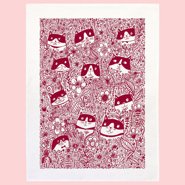Patterned tea towel with red cat and floral design on a pink background