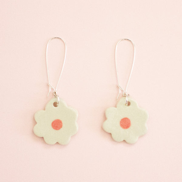 Flower-shaped earrings with a pink center on a light pink background