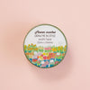 A round roll of washi tape labeled 'Flower market DRAW ME IN STYLE washi tape 20mm x 10 metres' with a colourful floral illustration, centered on a peach background.