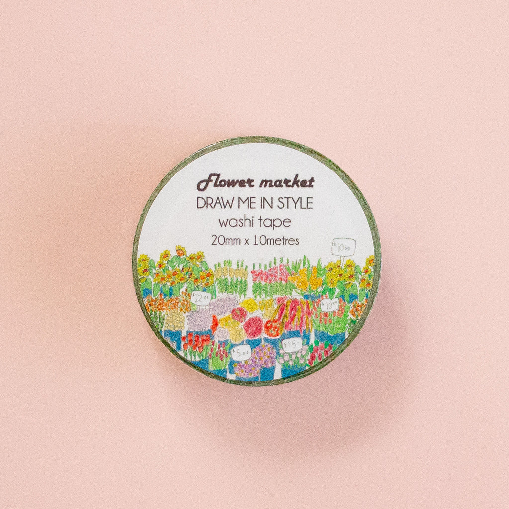 A round roll of washi tape labeled 'Flower market DRAW ME IN STYLE washi tape 20mm x 10 metres' with a colourful floral illustration, centered on a peach background.