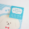 A close-up of a cute stationery set featuring a printed package card for a 'mini letter set' in light blue, placed over a matching printed sheet with a white dog face and red bow tie.