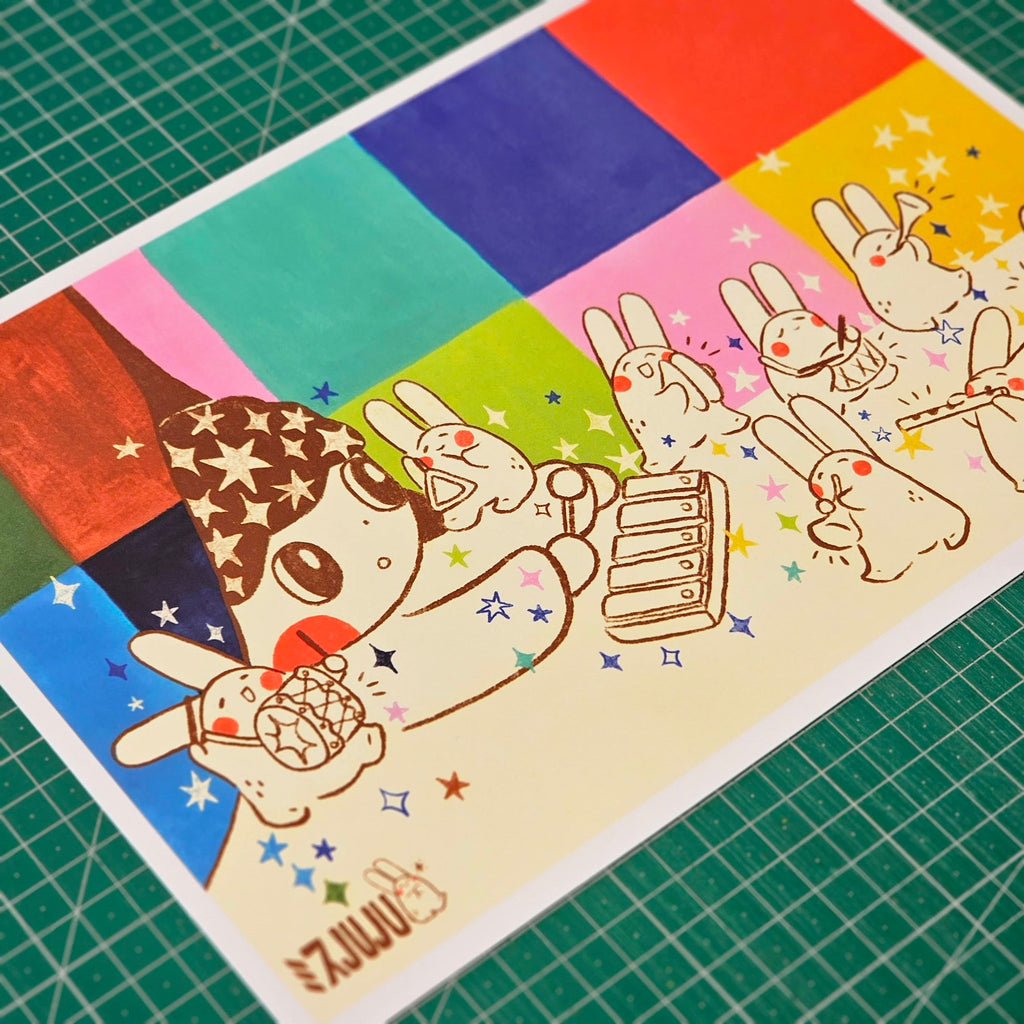 A square art print featuring a whimsical cartoon character with a star-patterned hat and colourful rainbow blocks in the background, placed on a green cutting mat.