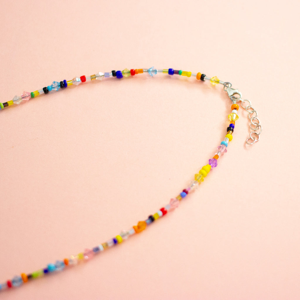 Colourful beaded necklace on a peach background