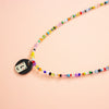 Colourful beaded necklace with a round pendant on a peach background