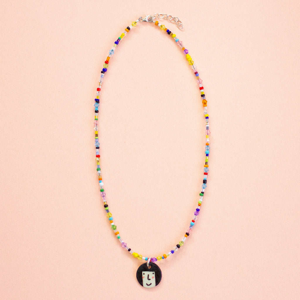 Colouful beaded necklace with a pendant on a peach background