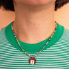 Person wearing a colourful beaded necklace with a pendant on a green and white striped shirt.