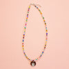 Colourful beaded necklace with a round pendant on a peach background