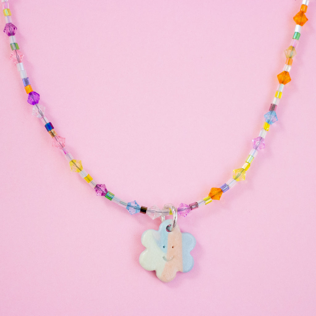 Colourful beaded necklace with floral charms on a pink background