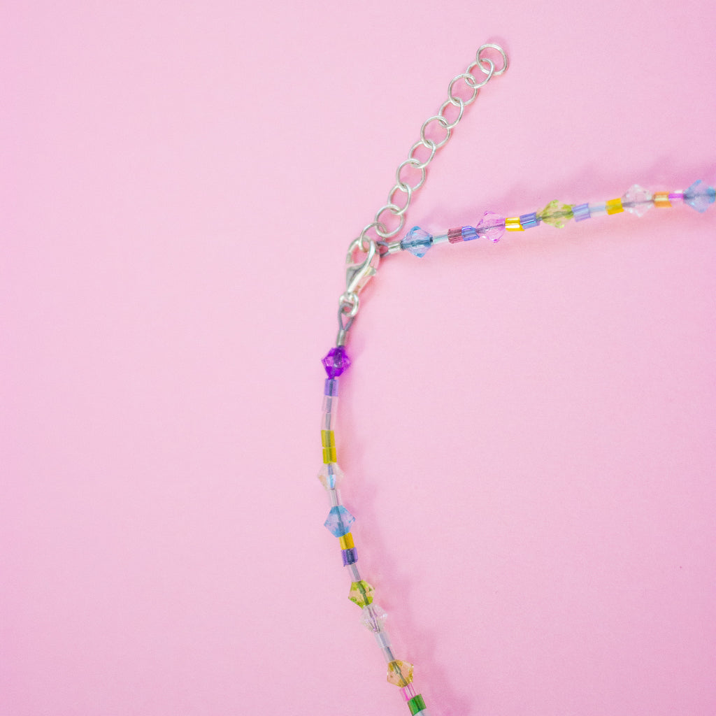 Colourful beaded necklace on a pink background
