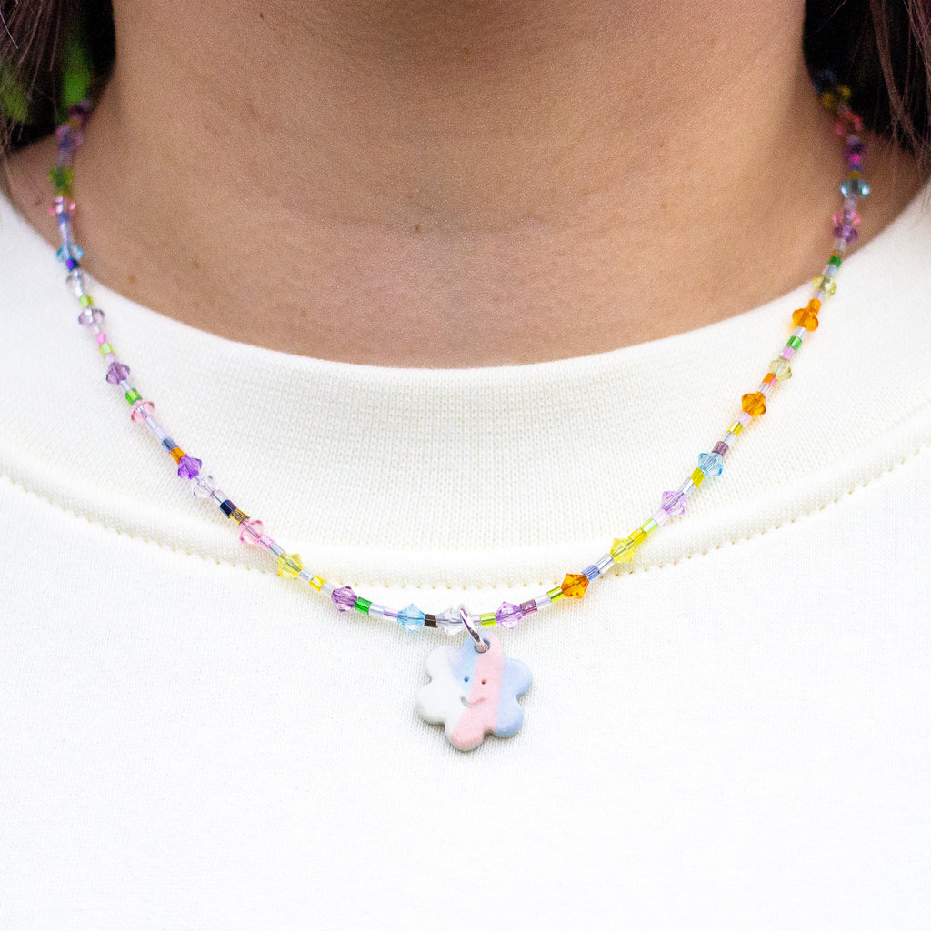 Colourful beaded necklace with a flower charm worn by a person on a white background