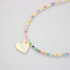 Colourful beaded necklace with a heart-shaped pendant on a light grey background