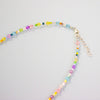 Colourful beaded necklace on a light grey background