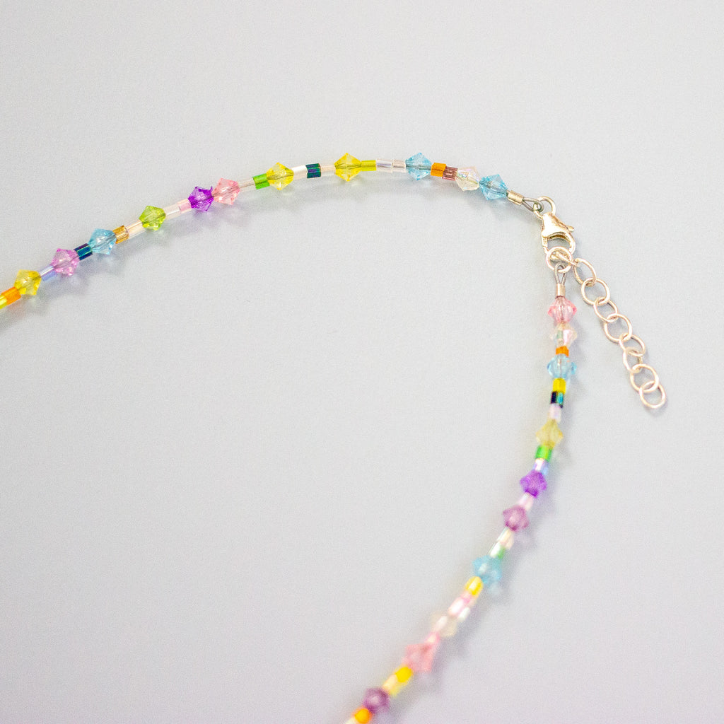Colourful beaded necklace on a light grey background