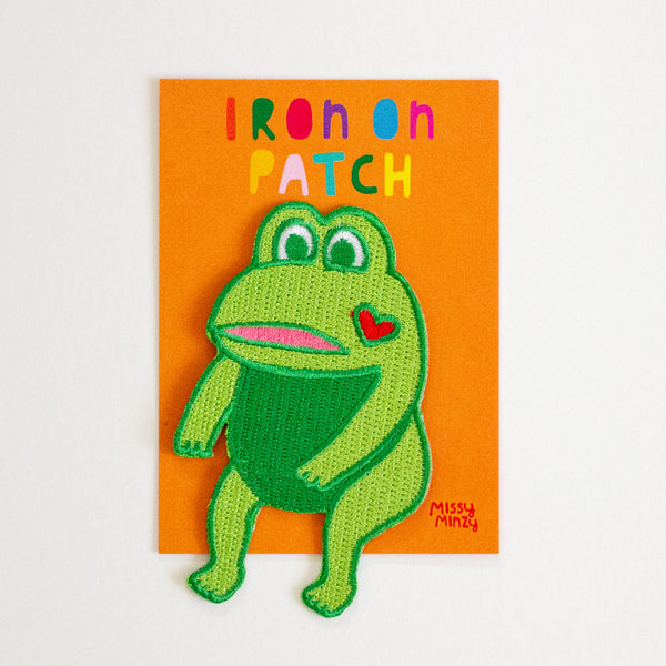 Green frog iron on patch with a heart on an orange card, brand 'Missy Minzy' visible.
