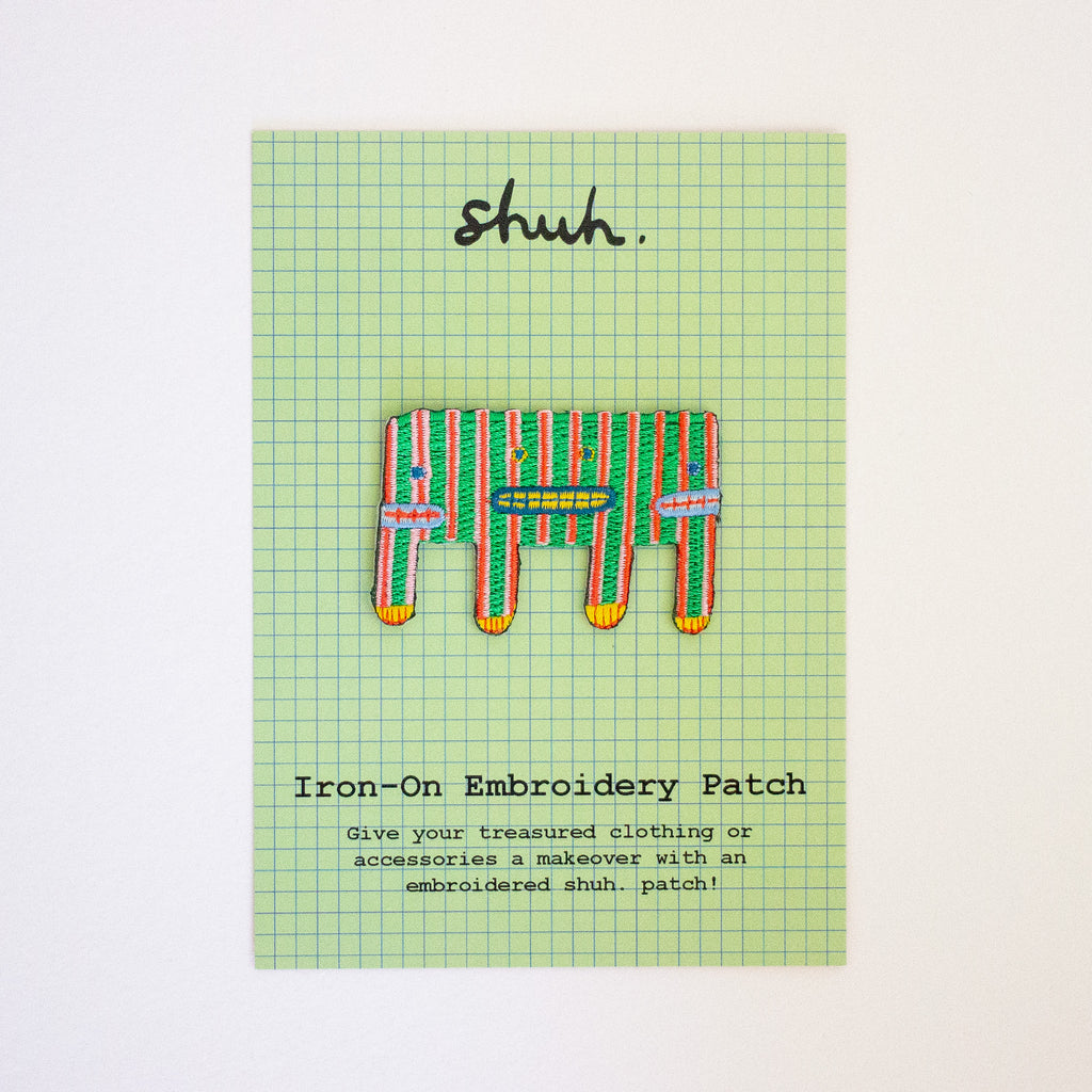 Iron-on embroidery patch with striped pattern on a green grid background