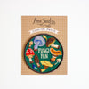 Iron-on patch with mushroom design and 'Fungi Fan' text on a cardboard backing, brand 'Anna Seed' visible.