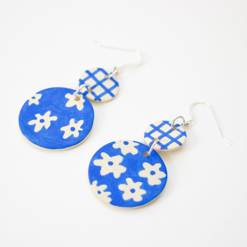Blue and white floral patterned earrings on a white background