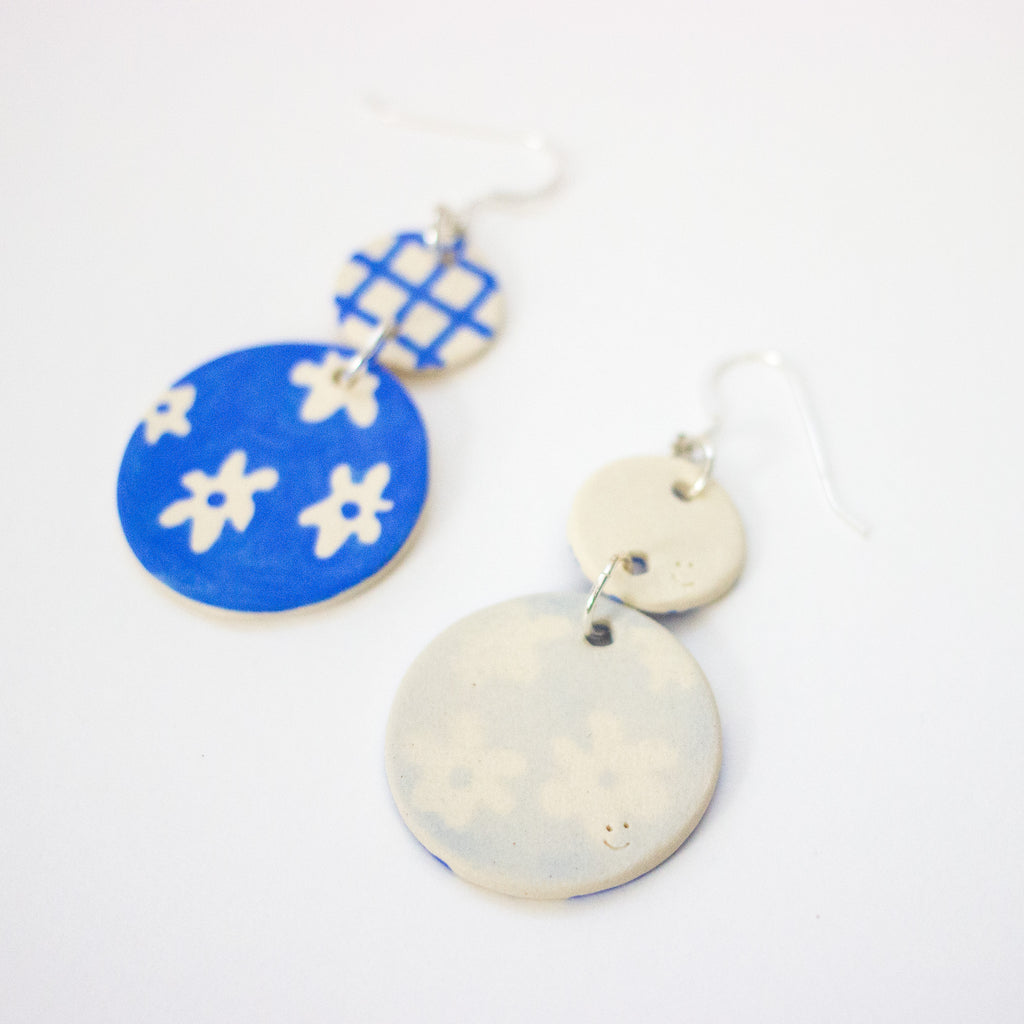Pair of earrings with blue and white floral designs on a white background