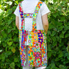Person wearing a colorful floral apron in front of green foliage