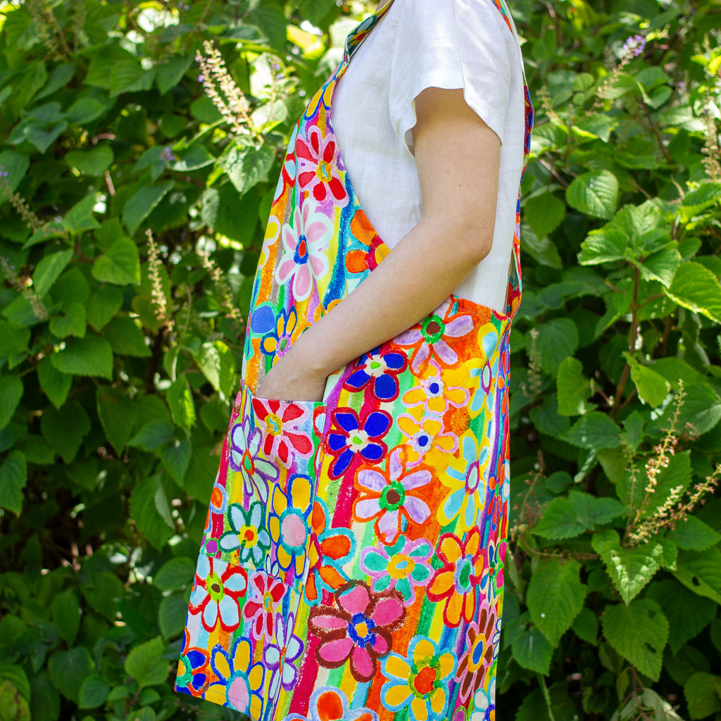 Person wearing a colorful floral apron in front of green foliage