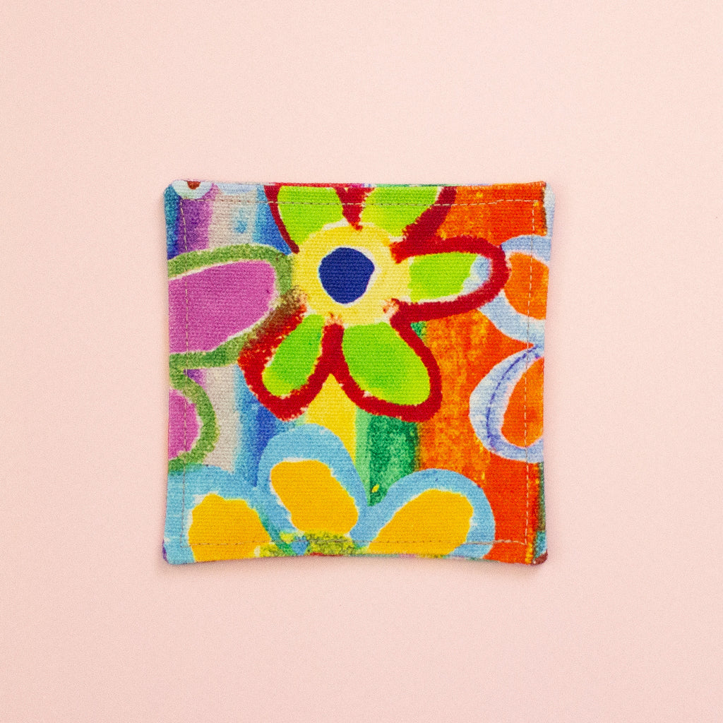 Colorful floral patterned fabric coaster on a pink background