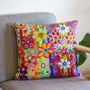 Colorful floral-patterned pillow on a gray couch with a plant in the background