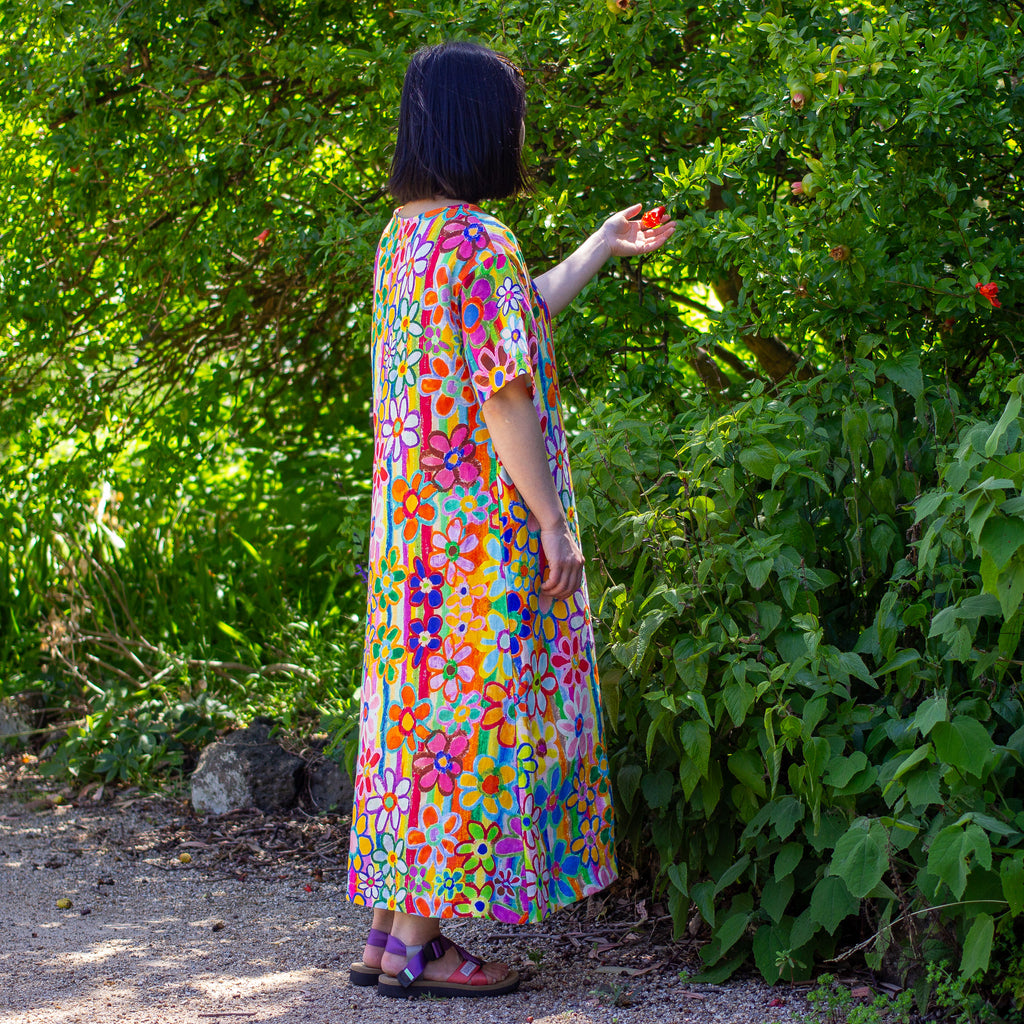 Woman in a colorful linen floral dress standing in a garden