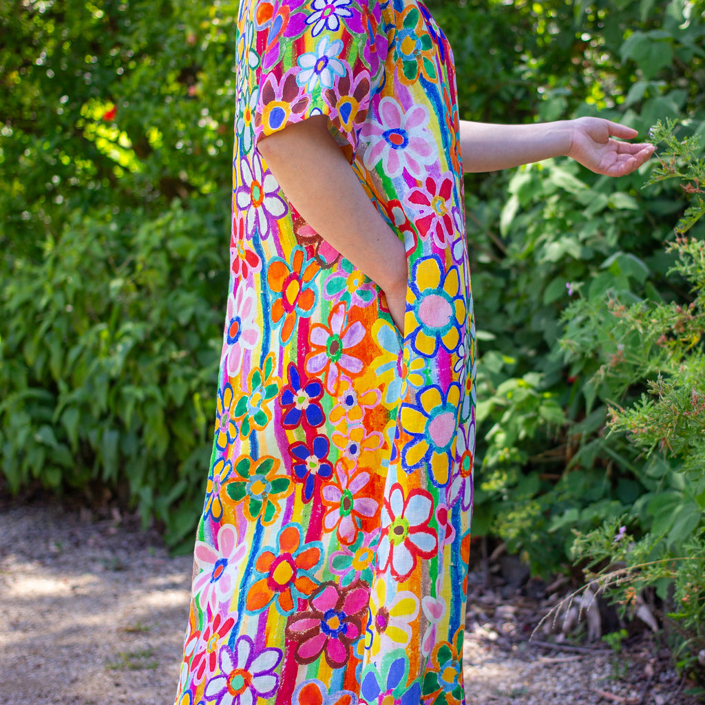 Person wearing a colorful linen floral dress standing outdoors with greenery in the background
