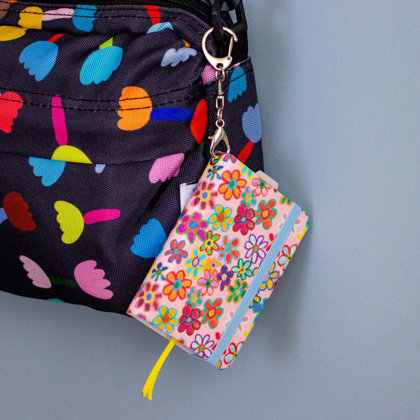 Colourful floral notebook with a keychain on a grey background