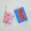 Floral notebook with keychain and blue box with orange card on a light green background