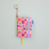 Floral-patterned keychain with a yellow ribbon bookmark on a light grey background