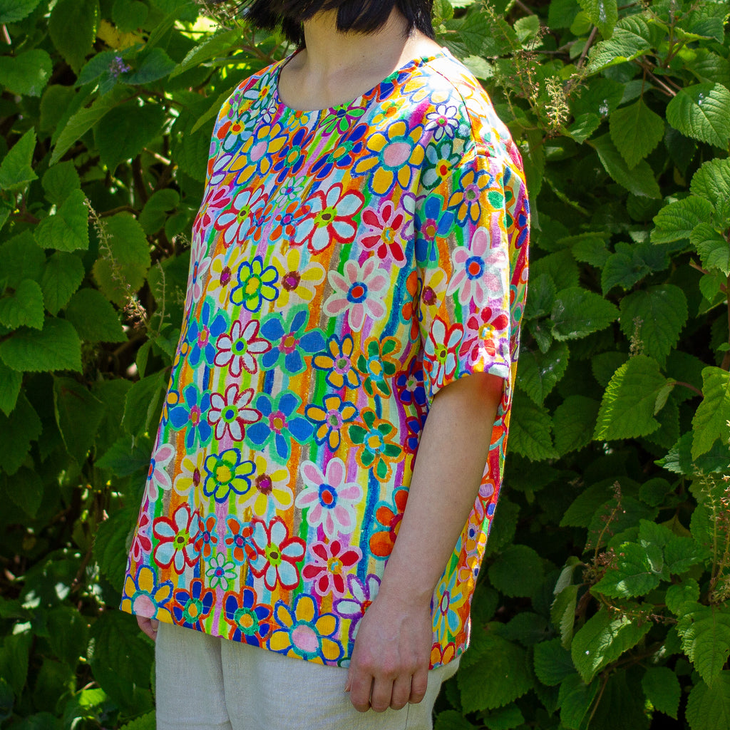 Person wearing a colorful floral linen shirt standing in front of green foliage