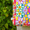 Colorful floral-patterned bag with a blurred green leafy background