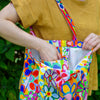 Person holding a colorful floral-patterned bag with a blurred green background
