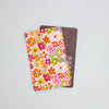 A colourful floral sticker over a dark grey card, against a light blue background.