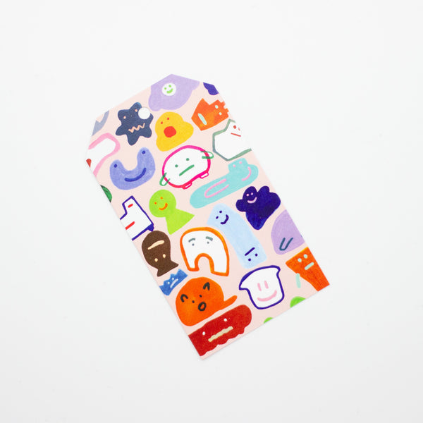 A closeup of the creatures gift tag. This print features a fun and whimsical gathering of quirky, wild characters, on a pink background. 