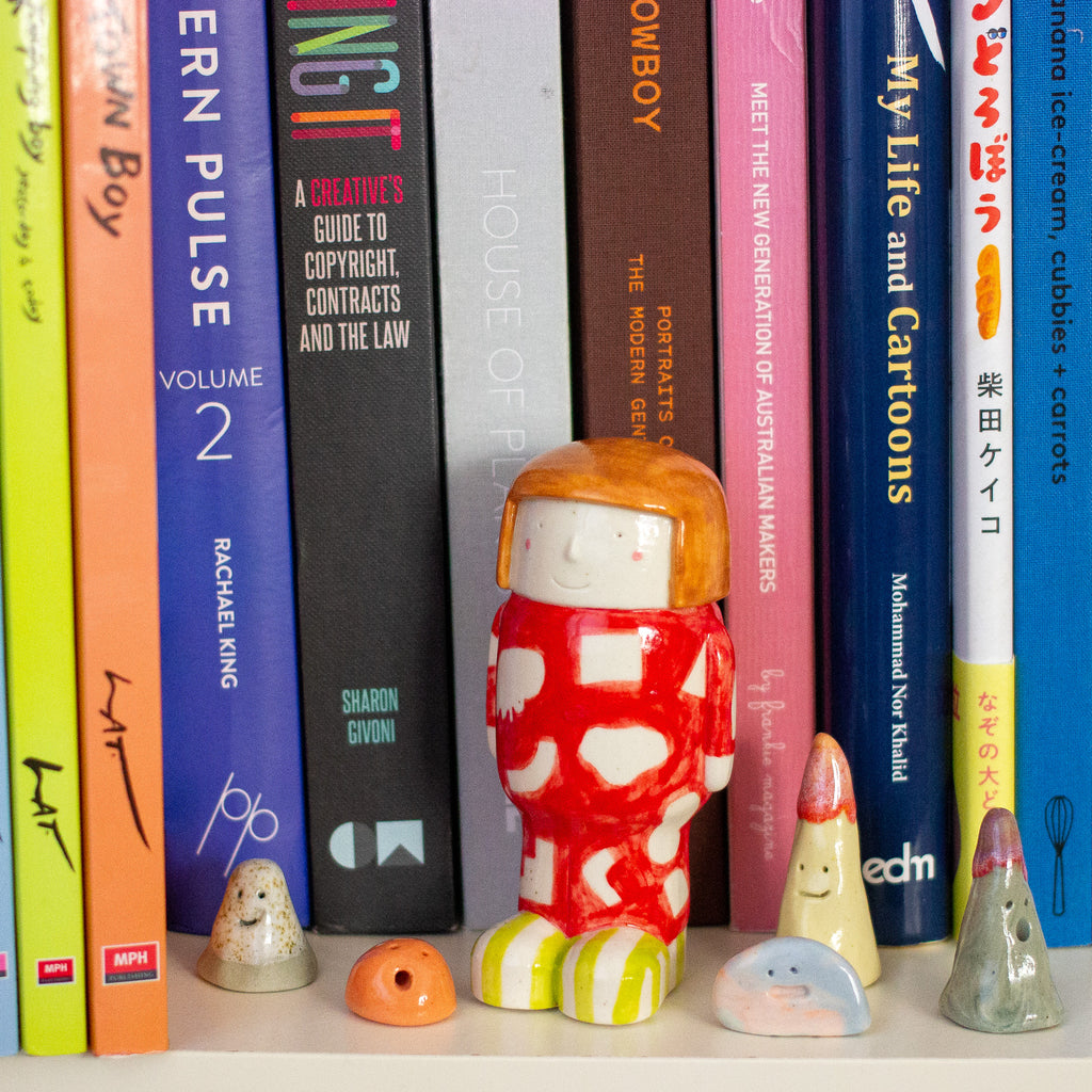 Colorful books with a small figurine in the center on a shelf