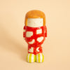 Ceramic figurine with a red patterned outfit on a beige background