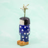 Ceramic vase shaped like a person with polka dot pants and a black hair on a light green background