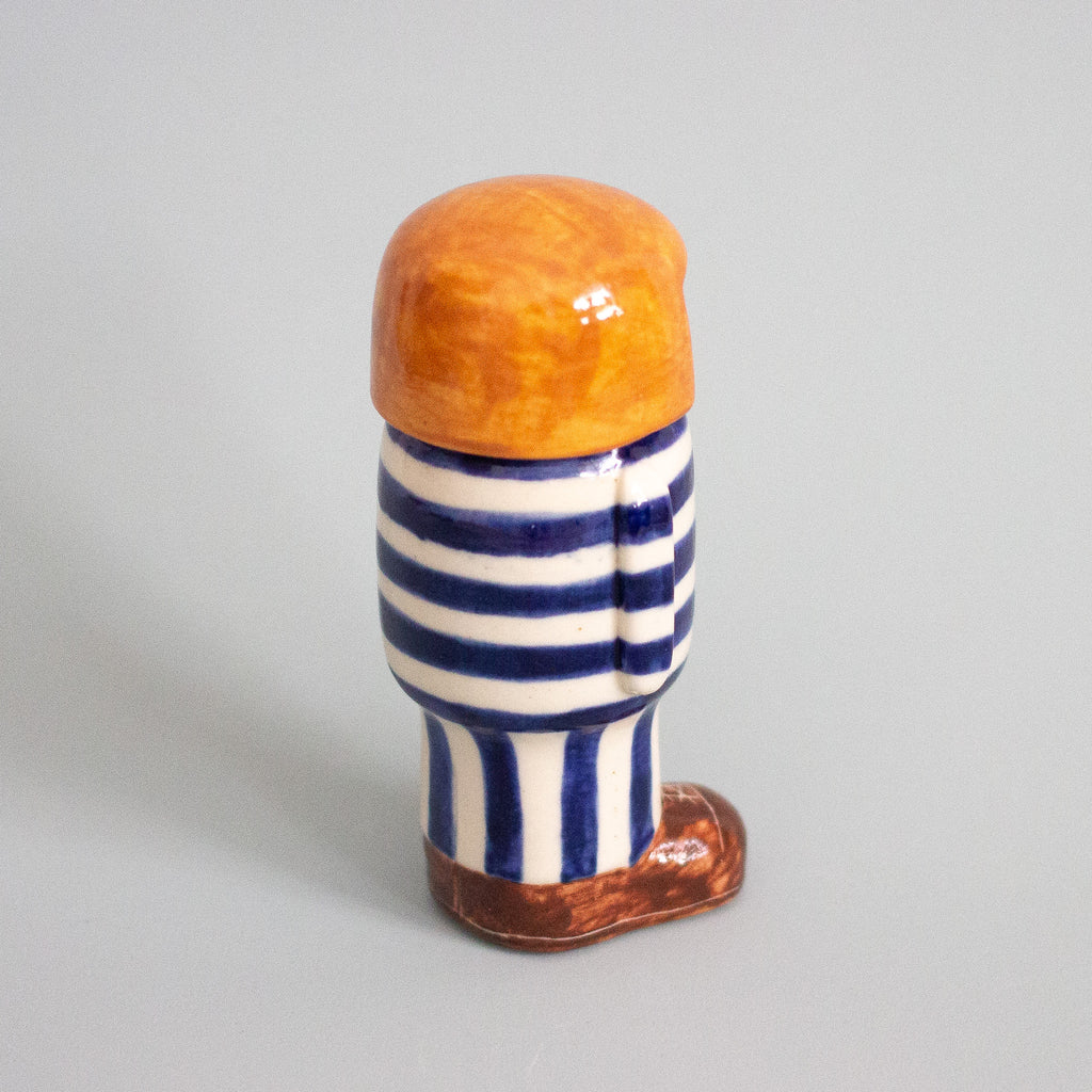 Ceramic figure with striped socks and orange hair on a gray background