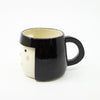 Black mug with a white face on a white background