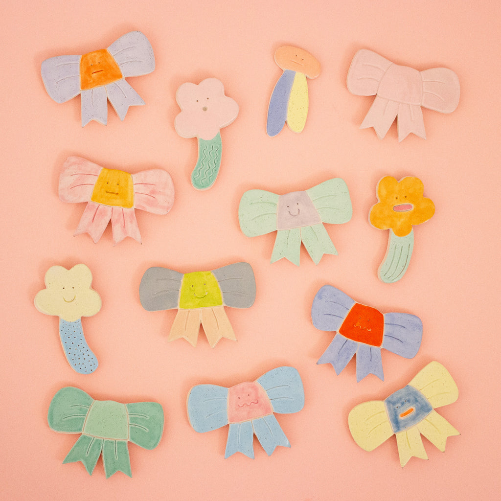 Colorful magnets including bows and flowers on a pink background